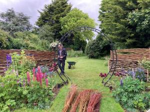 Cottage garden log stack 'dead hedge' with woven willow screen on top. 