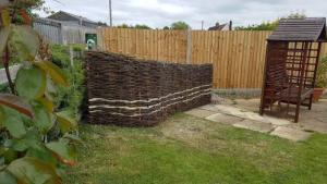 A mixed weave fence concealing a compost bin.